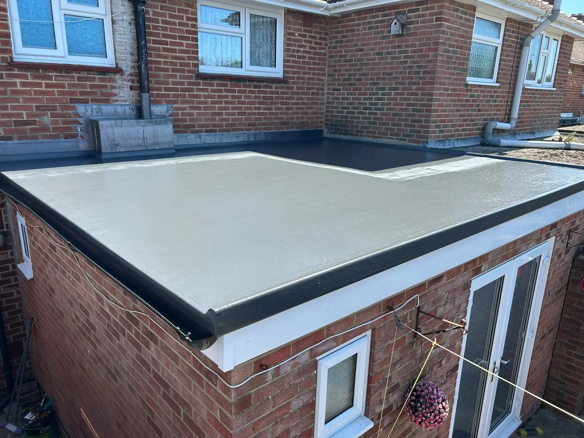 New fibreglass GRP flat roof with black edge trims on a rear extension in Hampshire