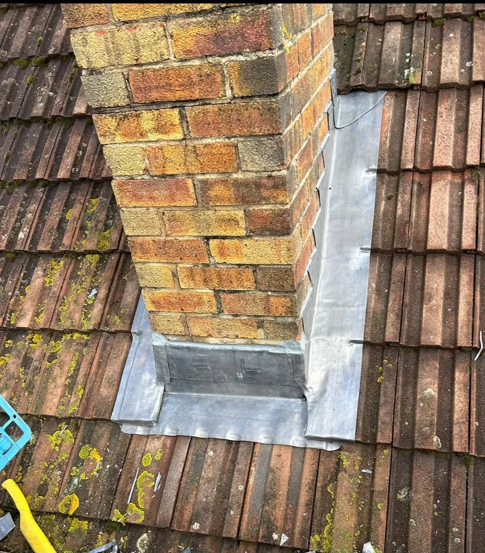 Repaired brick chimney with new hand-dressed lead flashing on a tiled roof